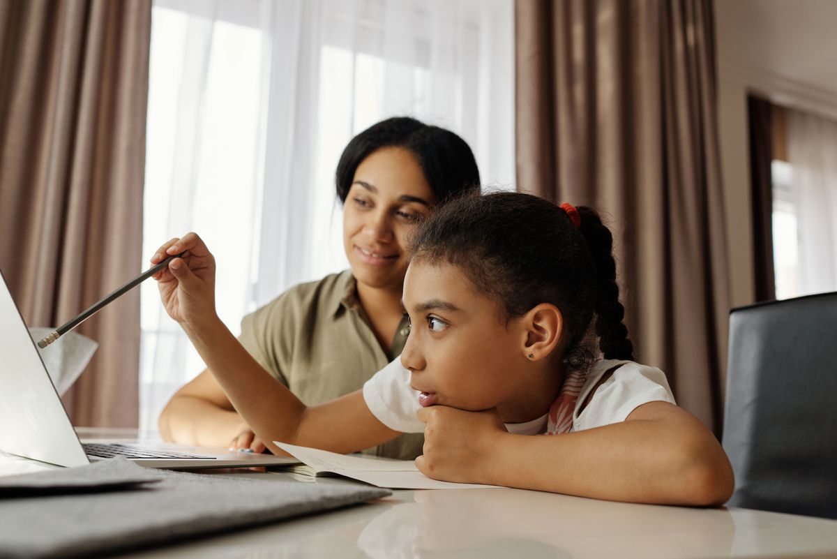 Mother helping her school-age daughter study at home