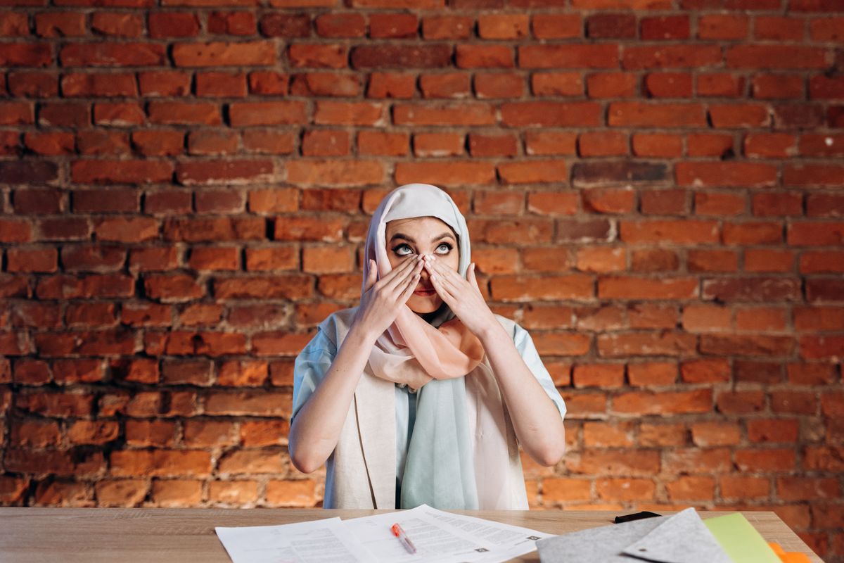 Pakistani professional feeling overwhelmed at her work desk